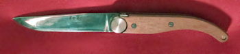 1994 : le "COUTELIA", Lame Z40C13  de 8 cm à blocage "liner-lock" haut - plaquettes bois vissées sur les platines - une partie de la platine arrière est découpée au laser et pliée vers le haut - par appui dessus avec le pouce, on libère la lame - second prix au Festival du couteau d'art de THIERS derrière le nouveau THIERS de DAVID - Le Tour de France en a commandé une grande quantité pour l'étape de Mende.